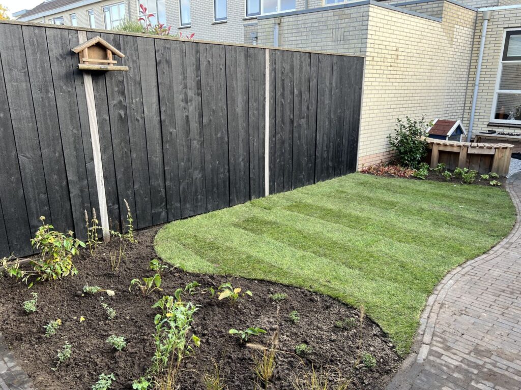 Tuinontwerp in Barneveld met gazon, gebogen border en zwarte houten schutting