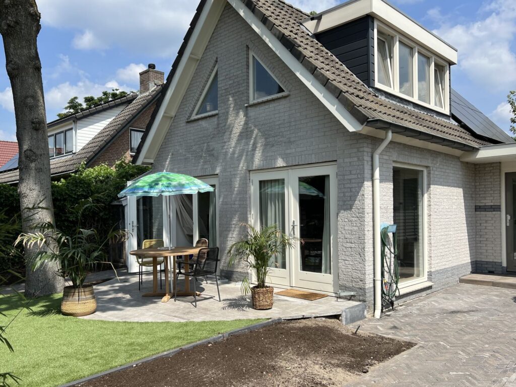 Tuinaanleg rond woning met terras en bestrating in Austerlitz